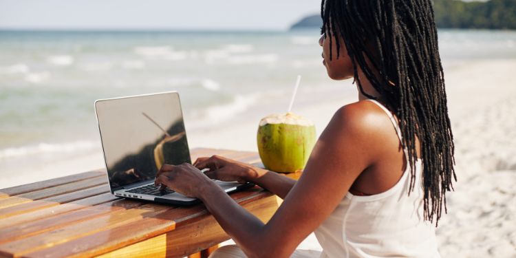 woman working by the beach on a laptop