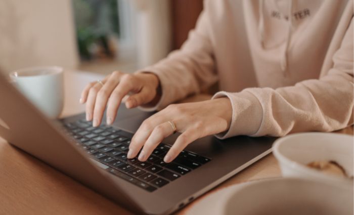 woman typing on her computer to transcribe