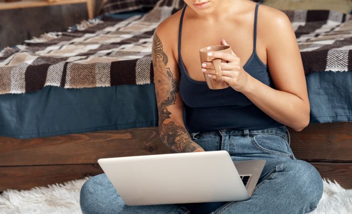 woman on her computer holding a cup of coffee