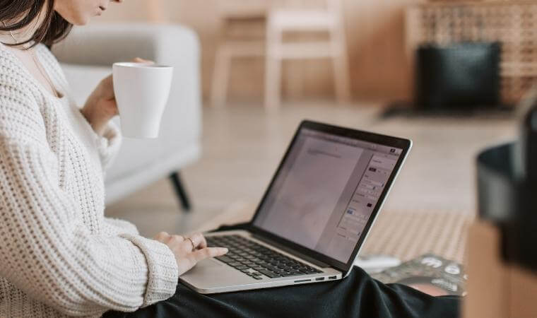 woman writing on a computer and drinking coffee