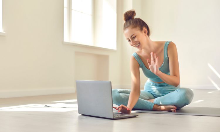 online fitness coach waving at her computer