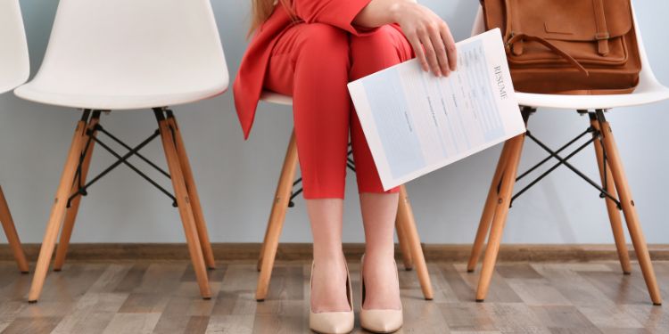 woman waiting in a chair with a resume in her hand