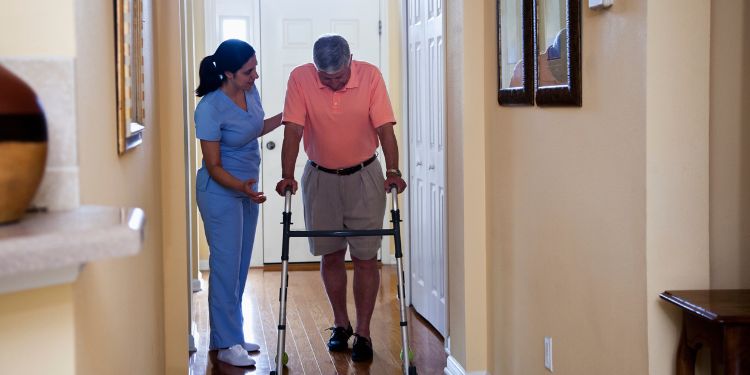 home health aide helping an older man walk