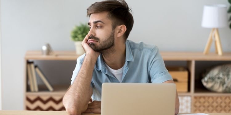 man feeling imposter syndrome sitting at his desk and staring out