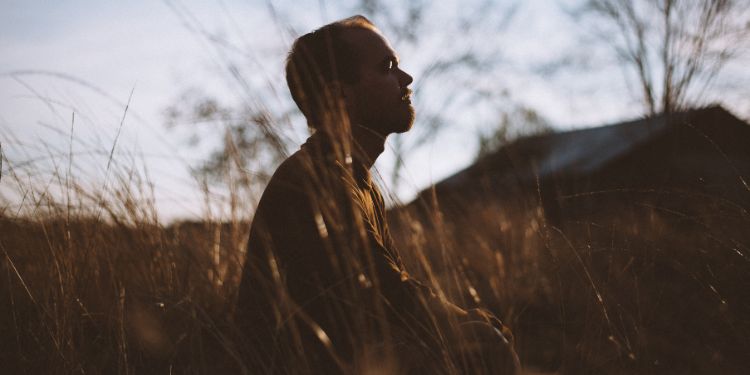 man meditating in a field