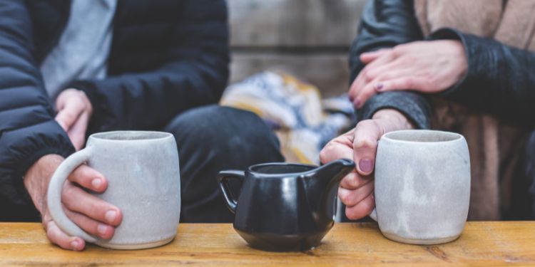 two people holding warm mugs next to each other