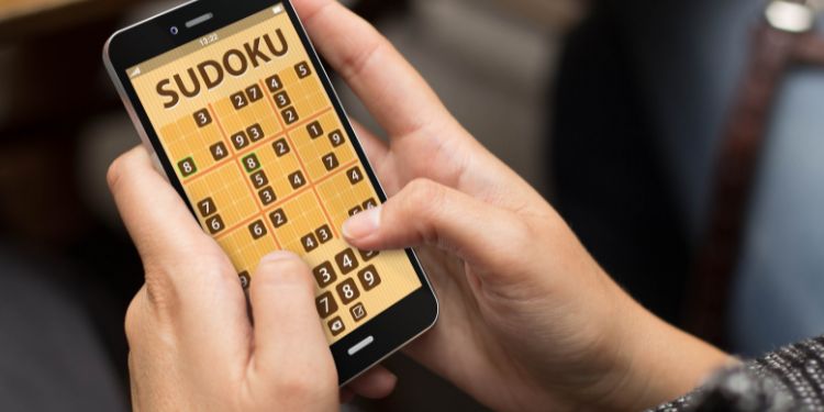 person holding a smartphone with a sudoku app open