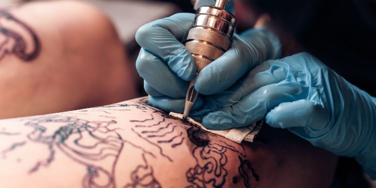 tattoo artist working on someone's tattoo