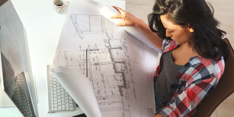woman sitting at a desk with architect blueprints