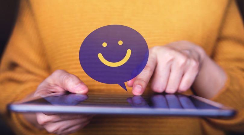 woman holding a tablet with a happy face graphic to illustrate happy clients