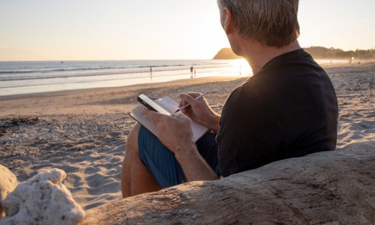 man journaling on a beach