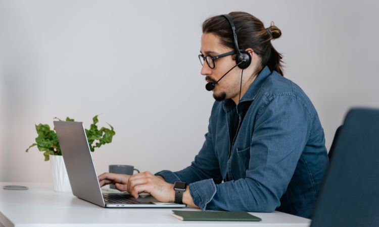 man typing on a computer with a headset